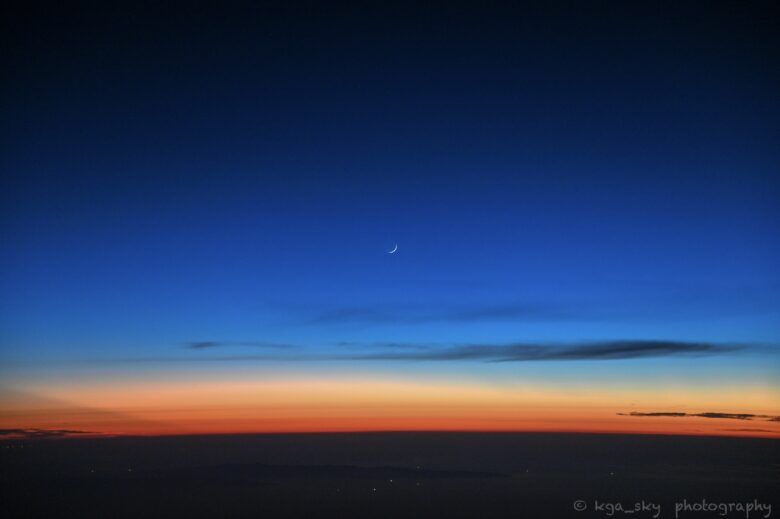飛行機機内から撮ったマジックアワーの夕焼けと月