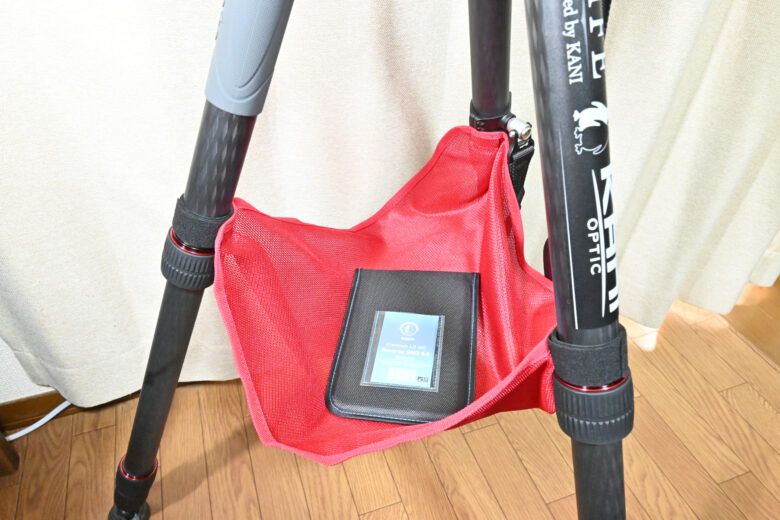 三脚にKANIのストーンバッグを取り付け、実際にストーンバッグの上にものを置いて視認性が上がっていることを説明